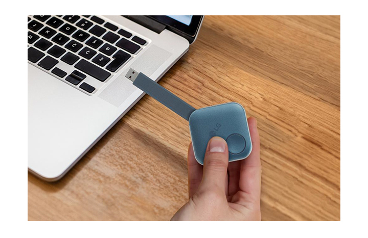 After pairing, you can share a screen with LG Signage by simply plugging a USB dongle device into the personal PC. This image shows a person is holding the USB dongle and try to connect it to the PC.
