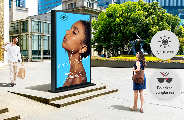 A large double-sided display is installed on the street, and a woman and man are looking at a vivid-quality advertisement on either side of the screen.