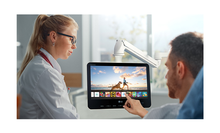 The patient is lying in the bed, touching the TV’s screen, and easily playing with an app.