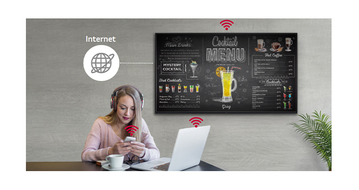 UL3J series is on the wall and a woman is using a personal PC and mobile phone. This image shows that the signage can operate as a virtual router so that the PC and mobile can be connected on the display to get wireless access.