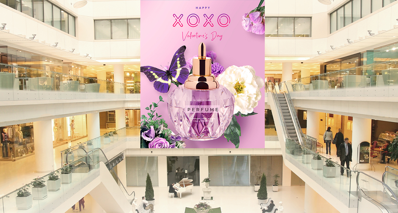 There are large LED displays installed across three floors of a large shopping mall, prominently showcasing perfume advertisements.