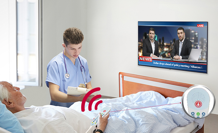 A patient lying in the bed is watching TV while listening to it through a pillow speaker.