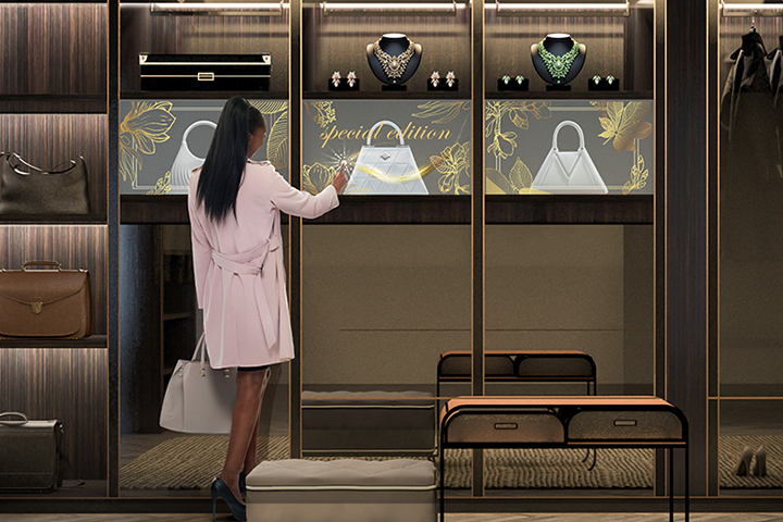 At an upscale store display, Transparent OLED Signage is installed as a woman interacts with the transparent screen, revealing patterns that seamlessly blend with the bags displayed behind the screen on the shelf.