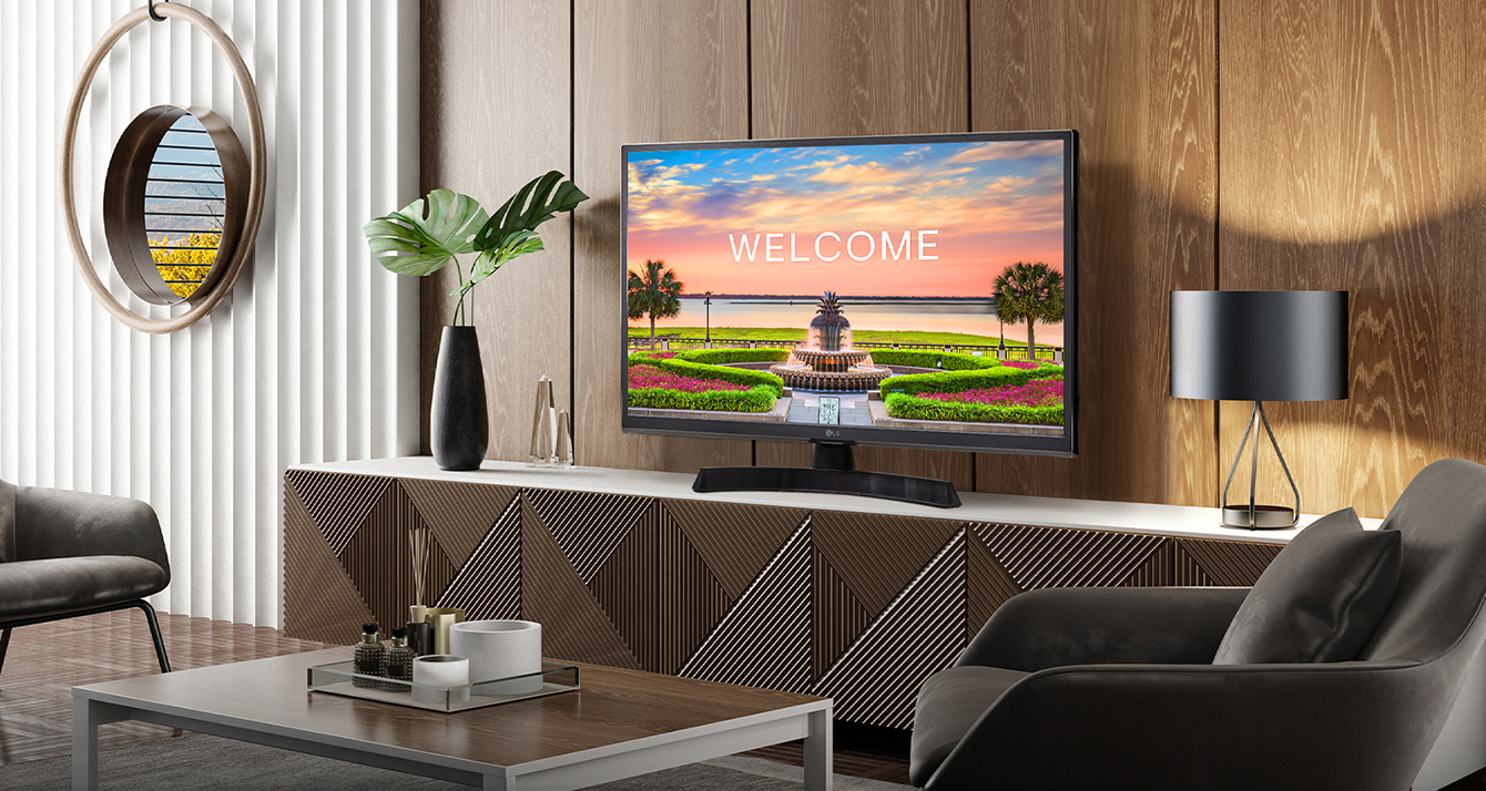 A TV is placed on the hotel room's main shelf, and a welcome message for guests is displayed on the screen.