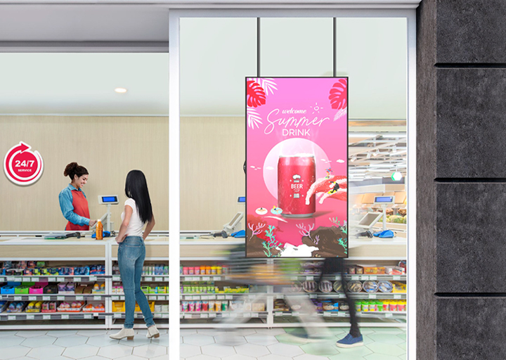 A large LED display is installed on the window inside the convenience store, vividly and brightly showcasing advertisements through the glass.