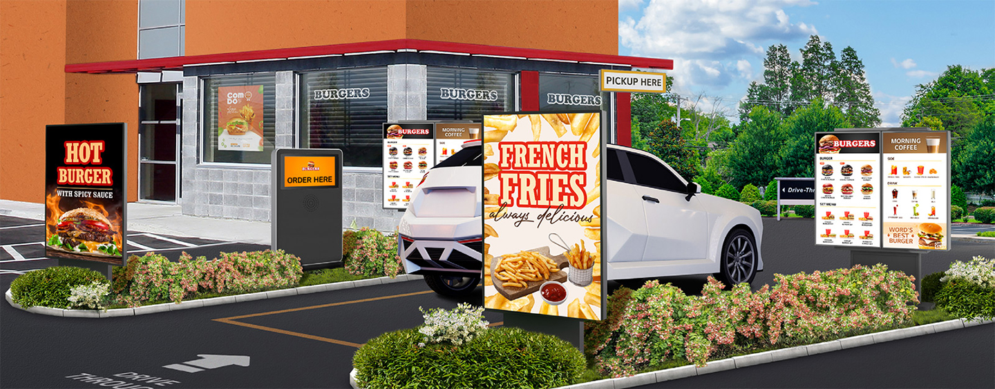 Several outdoor displays are installed at a burger place’s drive-thru, brightly and clearly showcasing the menu and food images.