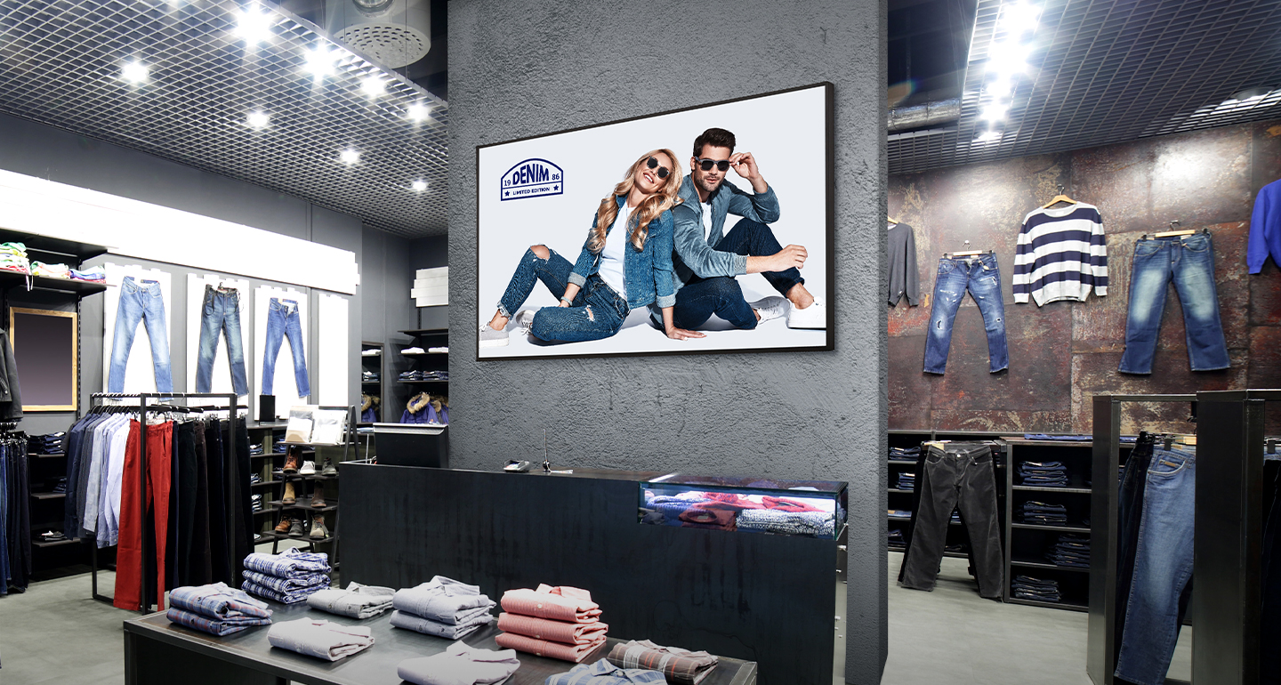 A signage display is installed on the central wall of the clothing store, displaying advertisements clearly and vividly.