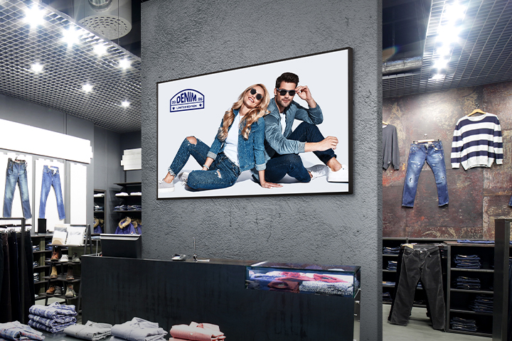 A signage display is installed on the central wall of the clothing store, displaying advertisements clearly and vividly.