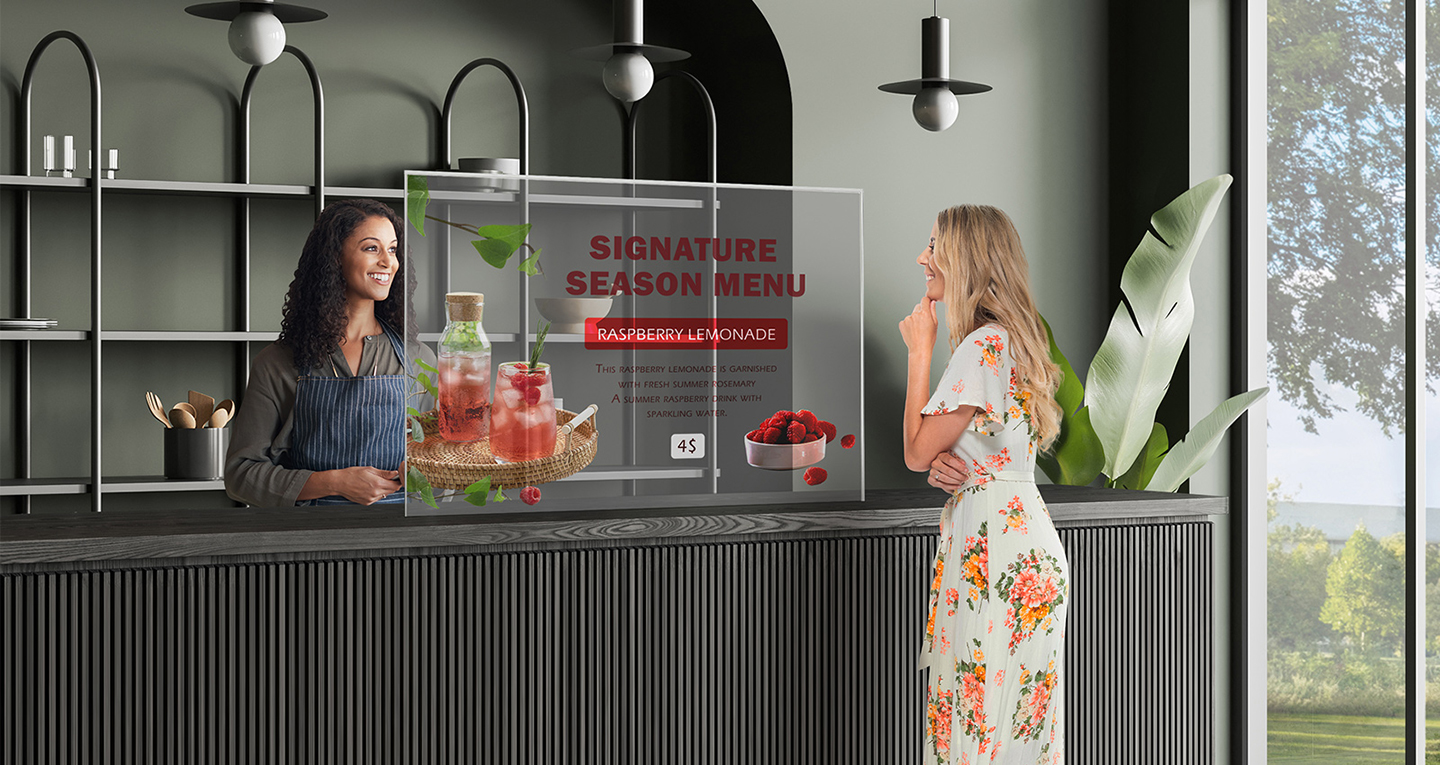 A cafe has Transparent OLED Signage installed, and a woman is checking the menu by looking at the Transparent OLED Signage screen